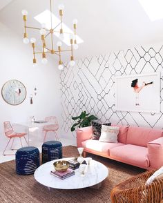 a living room with pink couches, chairs and rugs on the floor in front of a white wall