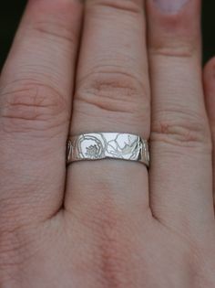 a woman's hand with a wedding ring on it, showing the engraving design