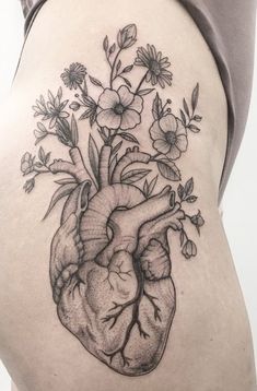 a woman's stomach with a flower and heart tattoo on the side of her thigh