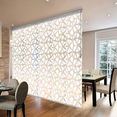 a dining room table and chairs are in front of a screen that has geometric designs on it