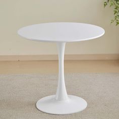 a white table sitting on top of a carpeted floor next to a potted plant