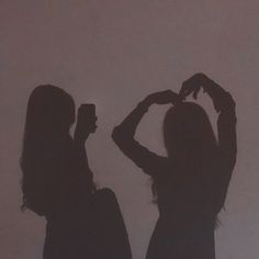 two women standing next to each other in silhouette