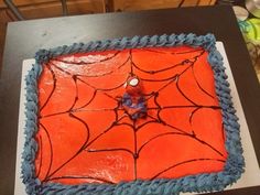 a spider web cake with blue icing on a black tableclothed surface in the shape of a square