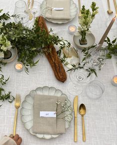 the table is set with plates, silverware and greenery for an elegant dinner