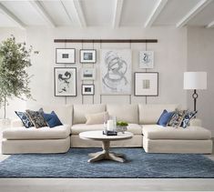 a living room with white couches and blue rugs on the floor in front of pictures