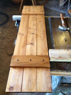 a wooden bench being built in a shop with some tools on the table next to it