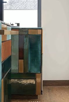 a cabinet with many different colored tiles on the front and back sides, along with a window