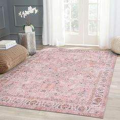 a pink area rug with an ornate design on the floor in front of a window