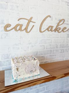 a cake sitting on top of a wooden table next to a sign that says eat cake