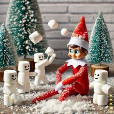 an elf is sitting in the snow surrounded by marshmallows