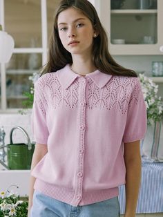 a woman standing in front of a kitchen sink wearing a pink sweater and blue jeans