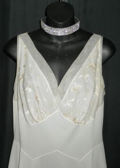 "Made by Vanity Fair, color is an off white, antique white, light beige, whichever you would like to call it, so pretty. This halter style gown is ultra flattering with satin stitched embroidery on the bust and chiffon trim on the bodice and hemline. I do see some light colored stains on the lower half of the gown, you may be able to see them in the photo of the hemline. I did launder but they didn't seem to come out. Relatively light so they aren't as obvious. Bust 38\" Waist 32\" Hips up to 46 Fitted Cream Nightgown For Wedding, Elegant White Nightgown With Bias Cut, Elegant White Bias Cut Nightgown, Elegant Beige Summer Nightgown, White Sleeveless Nightgown For Party, White Sleeveless Party Nightgown, Elegant Sleeveless Cream Nightgown, Elegant Cream Sleeveless Nightgown, Summer Wedding Nightgown Bias Cut