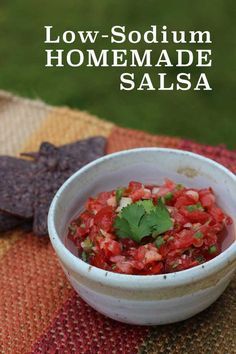 a white bowl filled with salsa sitting on top of a table next to tortilla chips