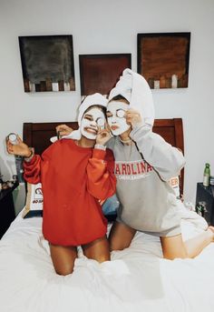 two people with face masks on sitting on a bed