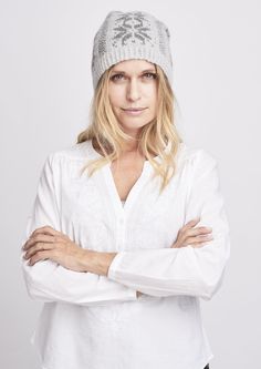 a woman with blonde hair wearing a white shirt and a gray knitted beanie