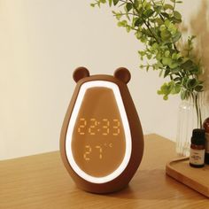 an alarm clock sitting on top of a wooden table next to a vase filled with flowers