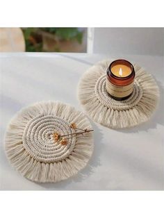 two candles are sitting next to each other on a white table cloth with a candle holder in the middle