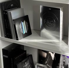 several cd's are sitting on the shelves in a room with white shelving