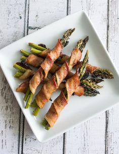 asparagus wrapped in bacon on a white plate