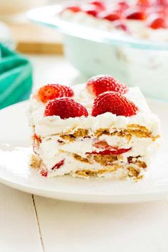 a piece of cake on a white plate with strawberries in the box next to it