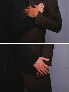 two men in suits embracing each other with their hands on their chests and arms crossed