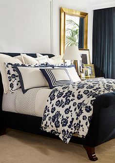 a bed with blue and white comforter in a bedroom next to a mirror on the wall