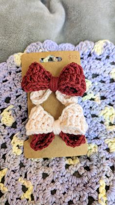 two crocheted bows sitting on top of a piece of paper in front of a blanket