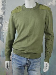 This Austrian vintage olive drab crew neck sweater has a tight stocking stitch knit and a ribbed crew neck, ribbed cuffs, and ribbed waistband. The army green military pullover has reinforced shoulder patches and button-down epaulets. Brand label: Rosenbauer, Austria Size: XL (42 to 44 US/UK) Material: 50% wool, 50% viscose Chest = 44 inches (111.76cm) Shoulders = 19.5 inches (49.53cm) Sleeve Length = 26.5 inches (67.31cm) (you can turn back the cuffs to your preferred length) Sweater Length = 2 Green Stretch Crew Neck Sweater, Olive Crew Neck Sweater For Fall, Green Crew Neck Knit Sweater, Fitted Green Sweater With Ribbed Cuffs, Olive Crew Neck Top For Winter, Military Style Green Winter Tops, Green Crew Neck Winter Sweater, Fitted Military Style Winter Tops, Vintage Green Sweater With Ribbed Cuffs