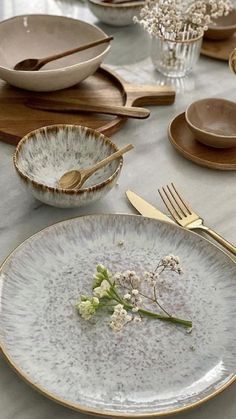 the table is set with plates, silverware and flowers in vases on it