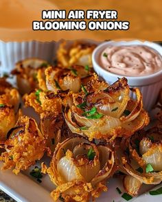 mini air fryer blooming onions on a white plate with dipping sauce in the background