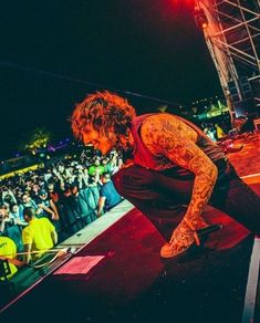 a man with tattoos on his arms and legs performing at a concert in front of an audience