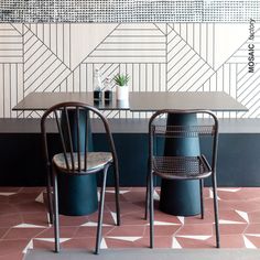 two chairs sitting next to each other in front of a wall with geometric designs on it