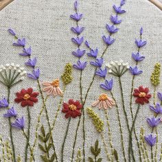 a close up of a embroidery on a piece of cloth with purple and red flowers