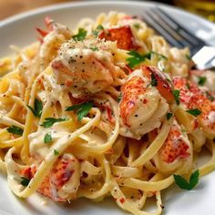 a white plate topped with pasta covered in lobster and cheese sauce next to a fork