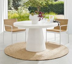 a white table with chairs around it and a potted plant in the center on top