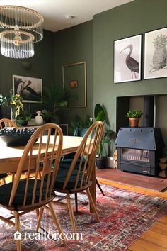 a dining room with green walls and pictures on the wall above the dinning table