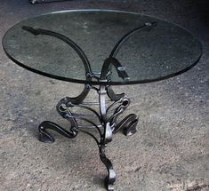 a glass and metal table with wheels on the bottom is sitting on concrete flooring