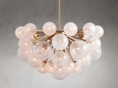 a chandelier with white glass balls hanging from it's golden metal frame