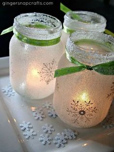 three mason jars with snowflakes and green bows are sitting on a white tray