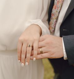 the bride and groom are holding hands with their wedding rings on their thumbnails