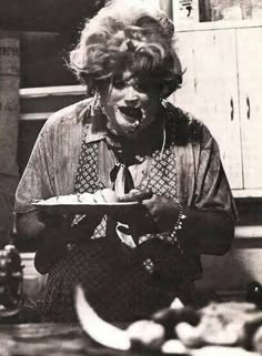 an old black and white photo of a woman holding a plate with food on it