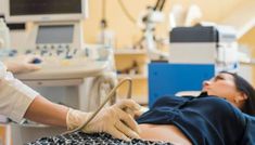 a woman laying in a hospital bed with her hand on the end of an iv tube