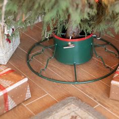 a small christmas tree is in a green pot on the floor next to presents and wrapped gifts