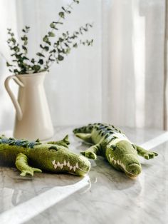 two stuffed alligators sitting on a counter next to a vase with flowers