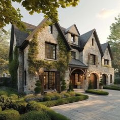 a large stone house with lots of windows and bushes in front of it, surrounded by greenery