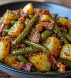 a black bowl filled with potatoes and green beans