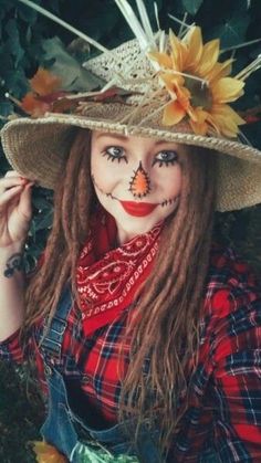 a woman wearing a scarecrow hat with flowers on her head and makeup painted to look like a clown