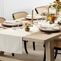 a dining room table set with place settings and flowers in vases on the table