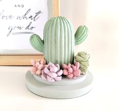 a small cactus plant sitting on top of a white table next to a framed photograph