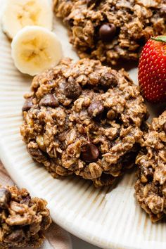 a plate topped with cookies covered in chocolate chips next to a sliced banana and strawberries